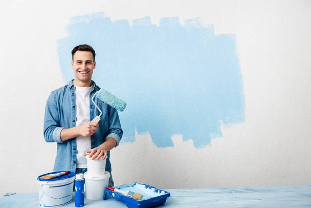Smiling young man with tools and paint - 写真・画像