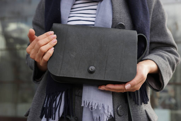 Omzunda küçük siyah bir çanta taşıyan bir kadın. - Fotoğraf, Görsel