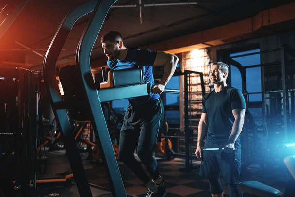 young man has workout with personal trainer in modern gym - Foto, Imagem