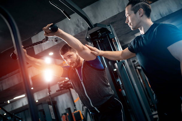 young man has workout with personal trainer in modern gym - 写真・画像