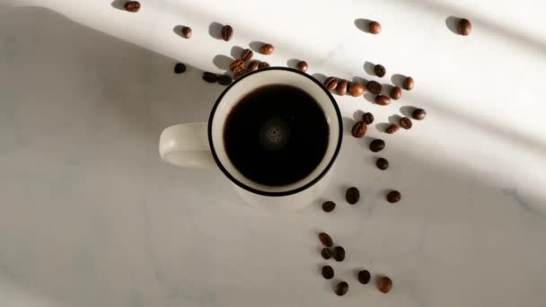 Womans hand stirring coffee in a cup on white marble table with beautiful light, top view - Metraje, vídeo
