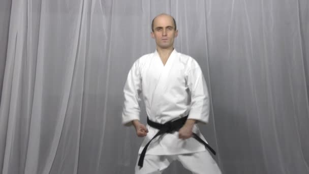 Sportowiec trenuje formalne ćwiczenia karate na lekkim tle - Materiał filmowy, wideo
