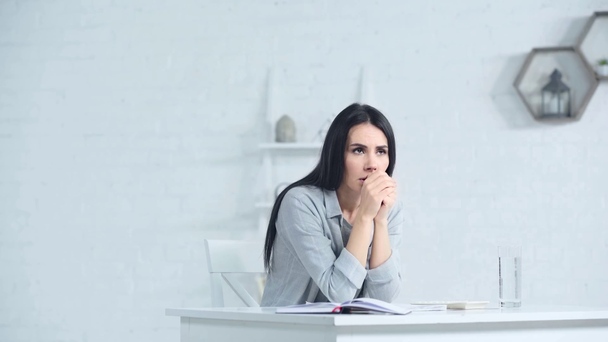 mujer preocupada tocando la cara mientras está sentado en el escritorio en la oficina - Metraje, vídeo