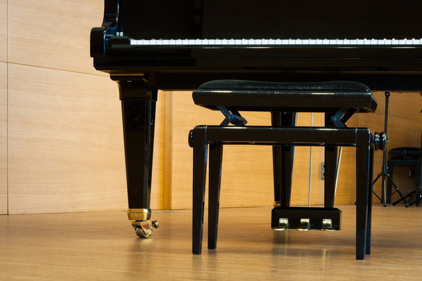 Partie du piano à queue avec tabouret de musique au sol
 - Photo, image