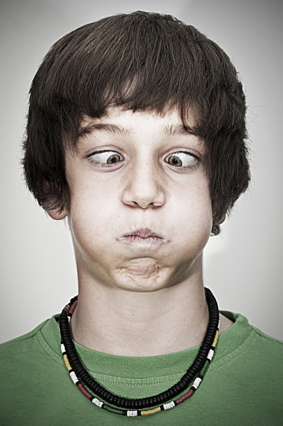 Porträt eines schielenden jungen Teenagers mit Halskette und grünem Pullover - Foto, Bild
