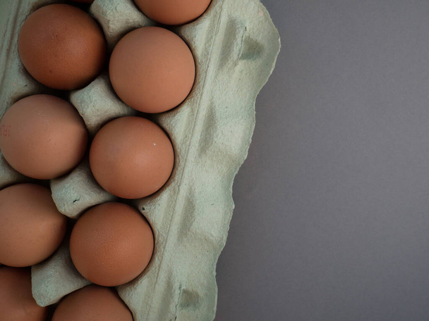 灰色の上に隔離された開いた卵のカートンの茶色の鶏の卵の全体像。新鮮な鶏の卵の背景。コピースペース付きのトップビュー。天然の健康食品や有機農業の概念。箱の中の卵 - 写真・画像