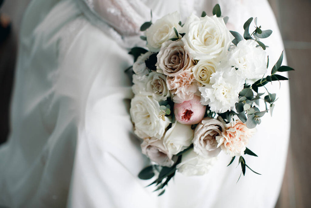 όμορφη νύφη κρατώντας γαμήλια ανθοδέσμη. Λευκά τριαντάφυλλα γαμήλια ανθοδέσμη  - Φωτογραφία, εικόνα