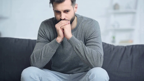 Besorgter Mann sitzt zu Hause auf Sofa  - Filmmaterial, Video