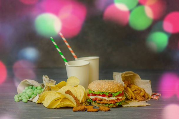 Boissons dans une tasse en papier avec deux tubes en papier et hamburger, collations salées, bretzels, chips
. - Photo, image
