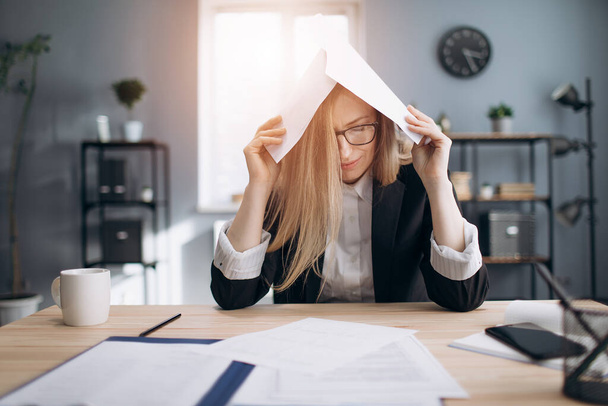 Tired lady stressing while working with paper documents - Фото, изображение