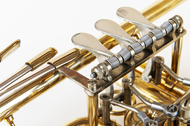 Válvulas de trompeta doradas plateadas en detalle con fondo blanco
 - Foto, imagen