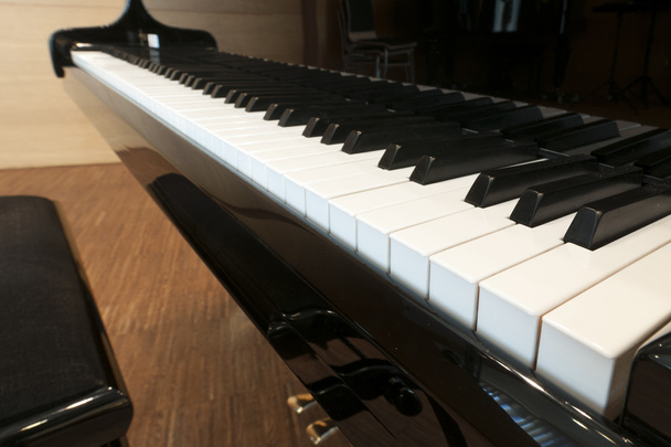 weiße Tasten der Tastatur eines schwarzen Konzertflügels mit Hocker und Pedalen - Foto, Bild