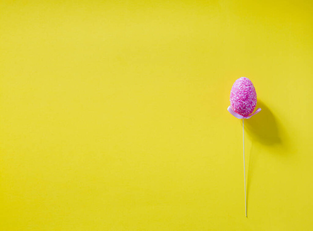 Easter pink sparkling decorated egg on yellow background. Minimal easter concept. Happy Easter card with copy space for text. Top view, flatlay. - Fotografie, Obrázek