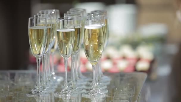 Vue rapprochée de plusieurs dizaines de verres à champagne élégants debout sur un plateau et préparés pour les invités d'un banquet de mariage en l'honneur de la mariée et du marié dans la salle des fêtes. Mariage jeunes mariés
. - Séquence, vidéo