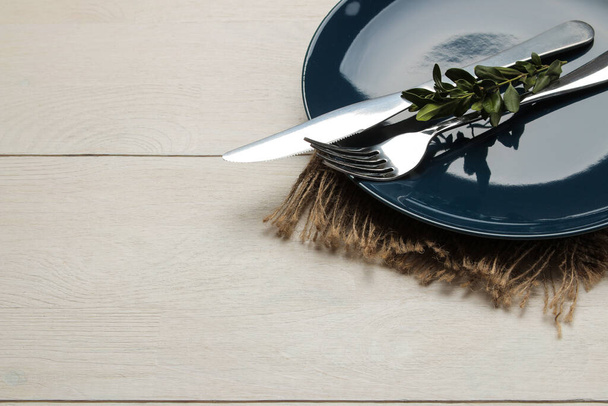Ρύθμιση τραπεζιού. Μπλε πιάτο και μαχαιροπήρουνα, πιρούνι και μαχαίρι σε λευκό ξύλινο τραπέζι.  - Φωτογραφία, εικόνα