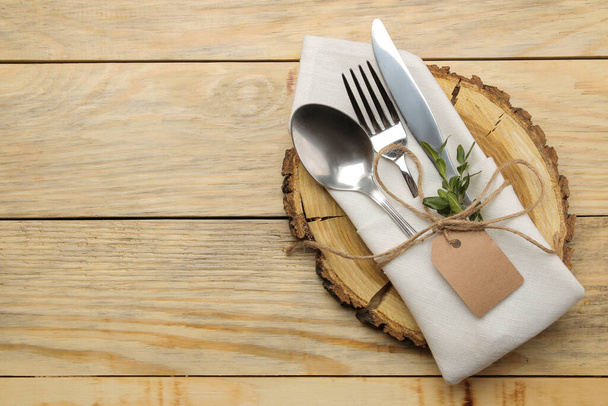 Tafelopstelling. houten standaard en bestek in een wit servet, vork, lepel en mes op een natuurlijke houten tafel. bovenaanzicht - Foto, afbeelding