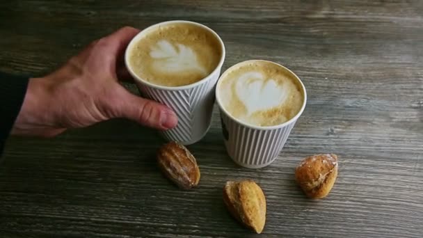 рука людини бере другу чашку з латте з іншої чашки кави
 - Кадри, відео