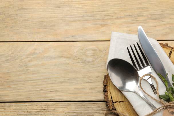 Apparecchiare. supporto in legno e posate in un tovagliolo bianco, forchetta, cucchiaio e coltello su un tavolo in legno naturale. vista dall'alto
 - Foto, immagini