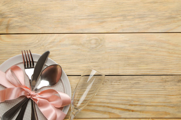 Tafelopstelling. Bord, glas en bestek vork, lepel en mes op een natuurlijke houten tafel. bovenaanzicht - Foto, afbeelding
