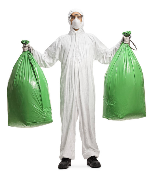 Full length portrait of a man in a decontamination suit holding plastic waste bags isolated on white background - Foto, Imagem