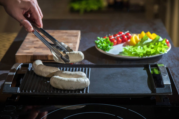 A cook turns over tongs of chicken to a grilled surface - Foto, Imagem