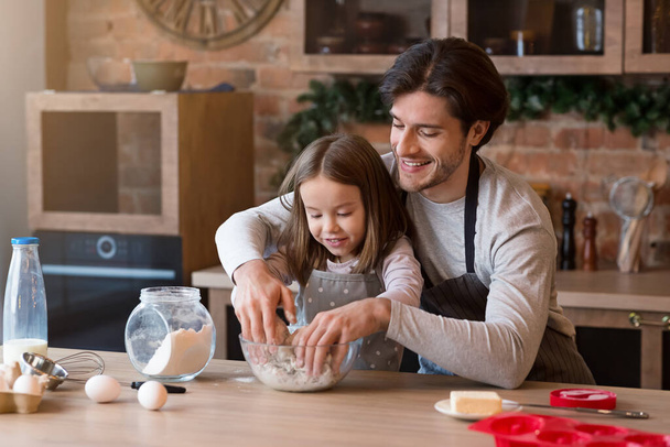 Père et fille faisant de la pâtisserie dans la cuisine ensemble, pétrissant la pâte
 - Photo, image