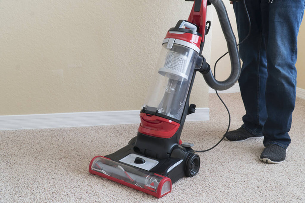 Очищувач вакууму використовується для чищення поверхні килима під час виконання домашніх завдань
 - Фото, зображення