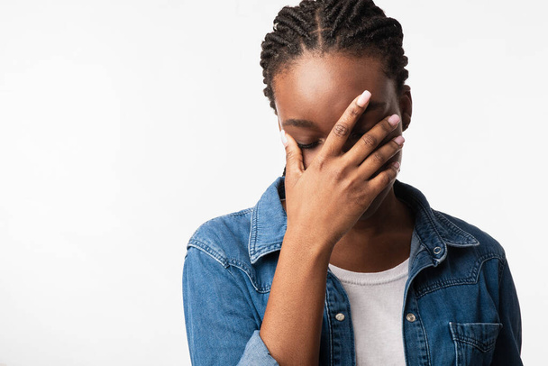 Afroamerikanerin bedeckt Gesicht mit Hand über weißem Hintergrund - Foto, Bild