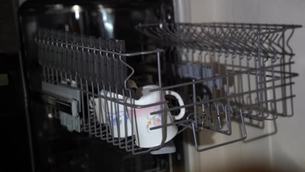 Women's hands make up in the dishwasher, white mugs with drawings and a white salad bowl - Footage, Video