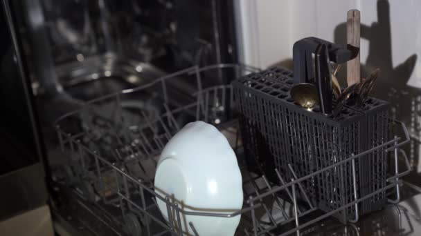 Kadın elleri bulaşık makinesini, kirli bulaşıkları, tabakları ve çatalları hazırlar. - Video, Çekim