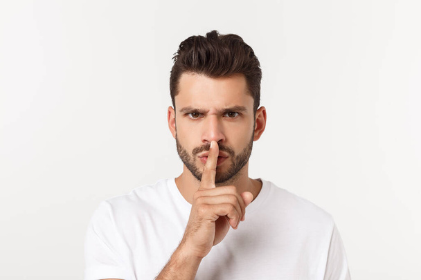 Homem de negócios com o dedo nos lábios pedindo silêncio sobre fundo branco
 - Foto, Imagem