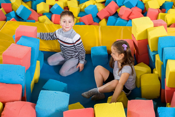 Діти грають з м'якими кубиками в сухому басейні в ігровому центрі. ігровий майданчик з піноблоками в батутському клубі
 - Фото, зображення