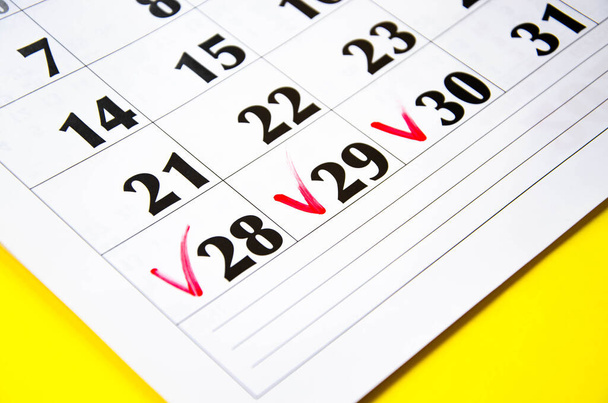 Checkmark on 28 29 30 numbers in the calendar on a yellow background. Mark on the calendar with a red marker. Calendar for plans, notes, meetings. Business calendar.  Copy Space - Photo, Image