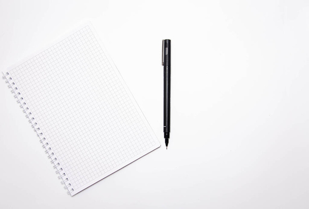 Cuadrado cuaderno con bolígrafo negro sobre un fondo blanco. Graba ideas, notas, planes, tareas. Cuaderno de vista superior y lateral. Flatlay. Copiar espacio
 - Foto, Imagen