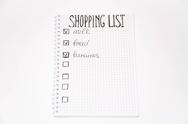 Lista de compras. Caderno quadrado com caneta preta sobre fundo branco. Grave ideias, notas, planos, tarefas. A lista inclui pão, leite, bananas. Espase de cópia
 - Foto, Imagem