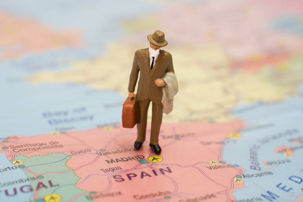 Σύκο του επιχειρηματία με βαλίτσα φορώντας ιατρική μάσκα στο χάρτη της Ισπανίας. - Φωτογραφία, εικόνα