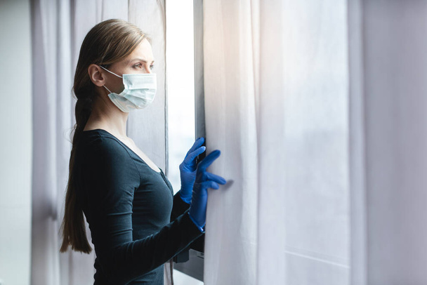 Bored woman in corona quarantine looking out of window - Fotoğraf, Görsel