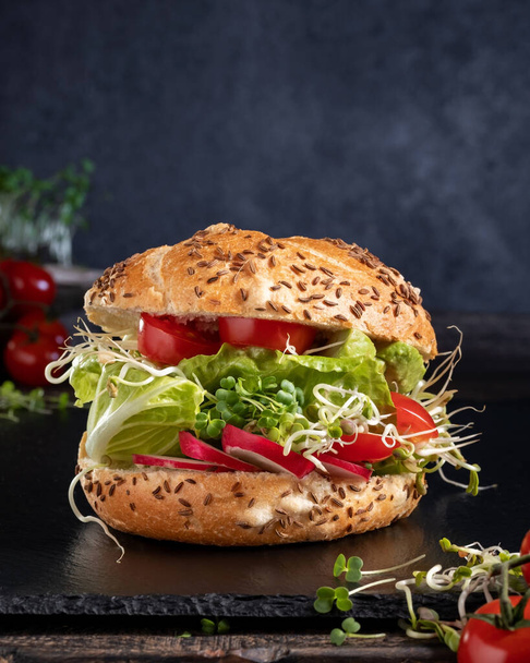 Veggie burger with fresh radish and fenugreek sprouts and broccoli microgreens - 写真・画像