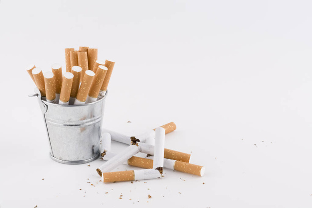 broken cigarettes next to a bucket of whole cigarettes - Foto, Imagem