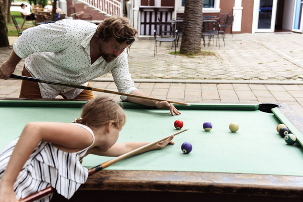 father with daughter playing billiards outdoors - Фото, зображення