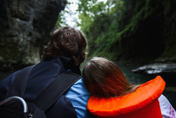 back view of people in life jackets in boat on river in canyon - Fotoğraf, Görsel