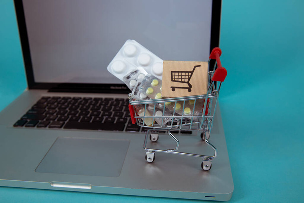 Mini shopping cart full of homeopathic remedies on laptop background. Homeopathy and internet online shopping. - Foto, immagini