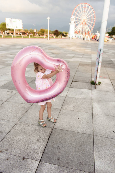 niña en vestido rosa con un juguete en la playa  - Foto, Imagen