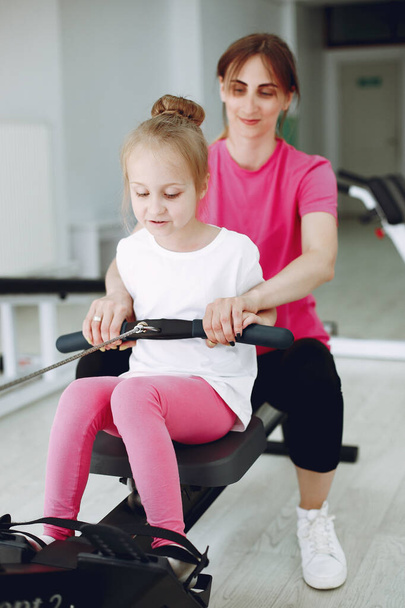 Mère avec petite fille sont engagés dans la gymnastique dans la salle de gym
 - Photo, image