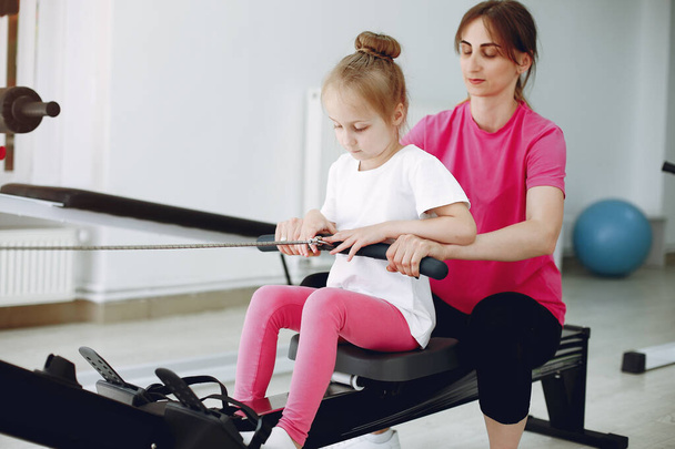 Mother with little daughter are engaged in gymnastics in the gym - Photo, image