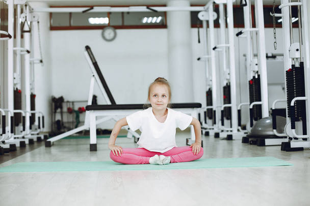 Cute little girl are engaged in gymnastics in the gym - Φωτογραφία, εικόνα