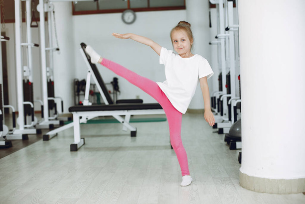 Cute little girl are engaged in gymnastics in the gym - Foto, Bild