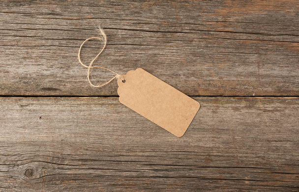 Étiquette en papier brun vide attachée avec une ficelle blanche. Prix, cadeau, étiquette de vente sur le fond en bois gris, gros plan
 - Photo, image