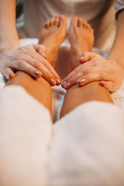 Close up photo of spa massage session made by a careful worker at the salon on the clients legs - Valokuva, kuva