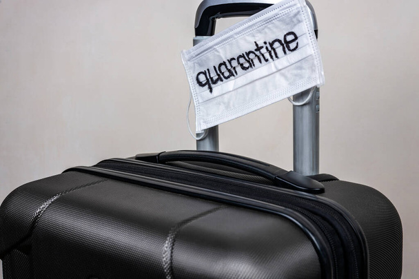 Suitcase with a medical mask and the inscription quarantine. The concept of the spread of coronavirus in the world. - Fotó, kép